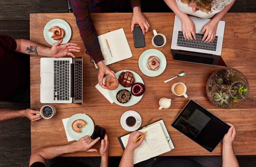 Agency folks working at a table with computers and donuts