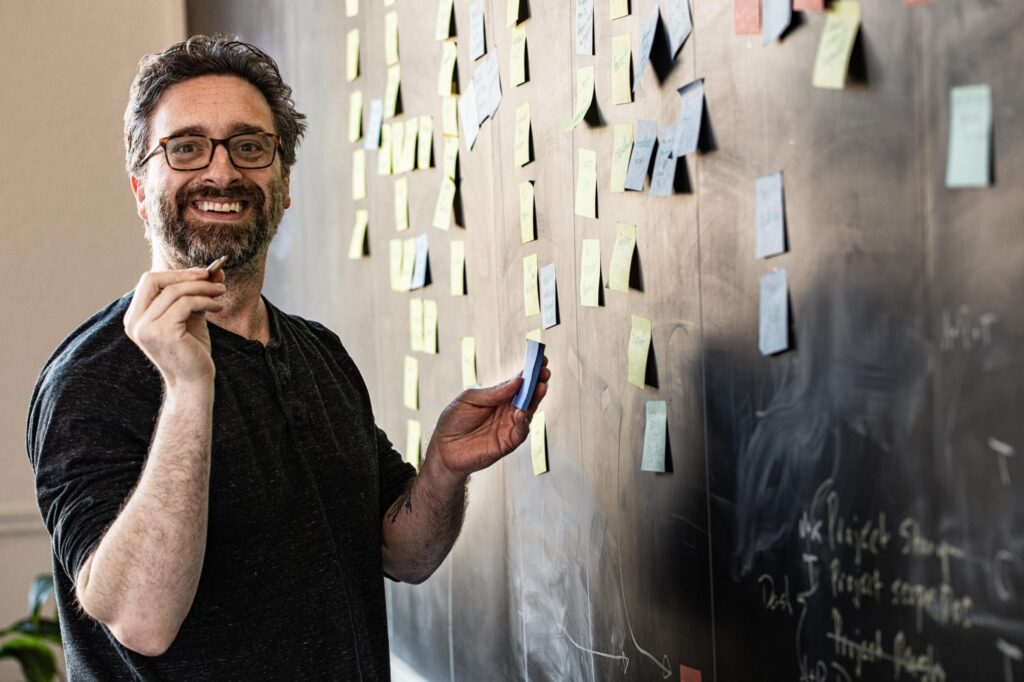 Chris Bolton standing next to board with post-its, organic lead gen specialist for agencies